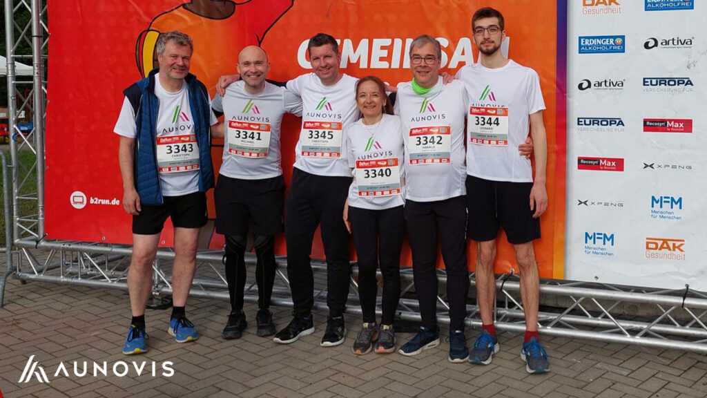 AUNOVIS Team beim B2Run 2026 in Karlsruhe vor der Fotowand.