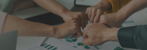 Fünf Hände stoßen mit Fäusten zusammen – Symbol für Teamwork